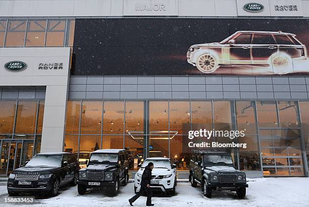 Pedestrian passes a selection of test drive automobiles outside a Jaguar Land Rover auto dealership in Moscow, Russia, on Thursday, Dec. 27, 2012....