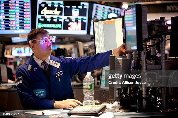 Traders wear 2013 New Years party glasses while they work on the floor of the New York Stock Exchange December 31, 2012 in New York City. US...