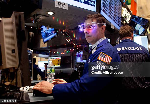 Traders wear 2013 New Years party glasses while they work on the floor of the New York Stock Exchange December 31, 2012 in New York City. US...