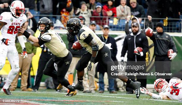 Zac Stacy of Vanderbilt eludes the tackle of Brandan Bishop of N.C. State to score in the Franklin American Mortgage Music City Bowl at LP Field in...