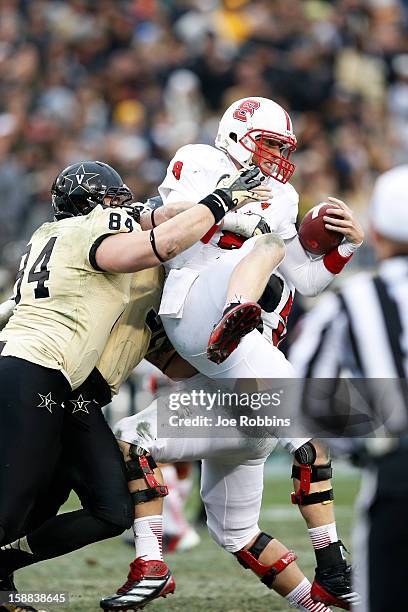 Mike Glennon of the North Carolina State Wolfpack gets sacked by Rob Lohr of the Vanderbilt Commodores during the Franklin American Mortgage Music...
