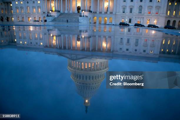 The U.S. Capitol is seen reflected in Washington, D.C., U.S., on Monday, Dec. 31, 2012. The U.S. House of Representatives doesn't plan any votes on...