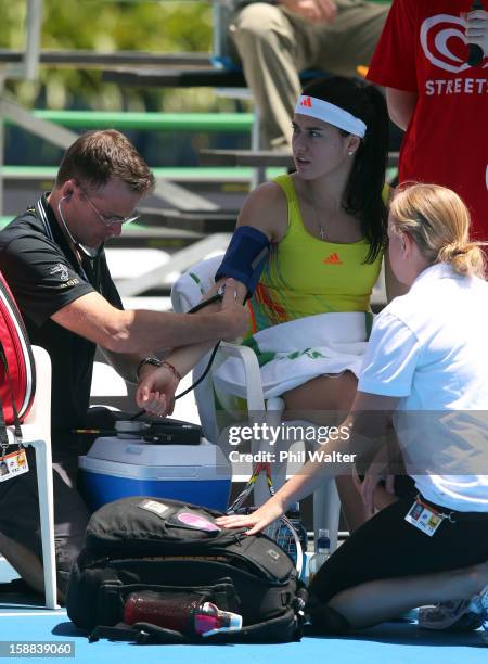 Sorana Cirstea of Romania is treated by medical staff before retiring in her first round match against Heather Watson of Great Britain during day two...