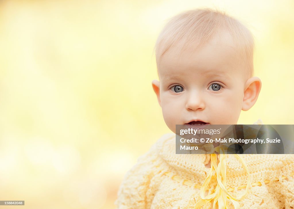 Bright-eyed baby girl in yellow sweater