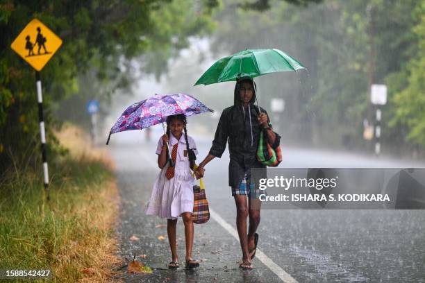 In this photograph taken on August 9 children make their way along a street during heavy downpour in Kilinochchi.