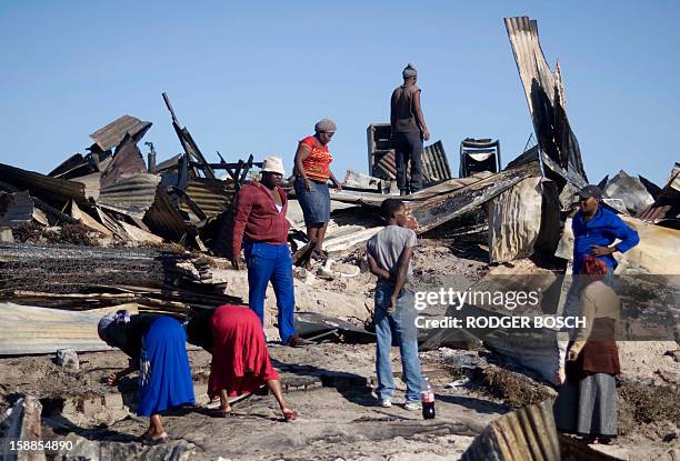 People look through the remains of burnt homes after a fire raged through the BM Informal Settlement, in Khayelitsha, on January 1 in Cape Town....