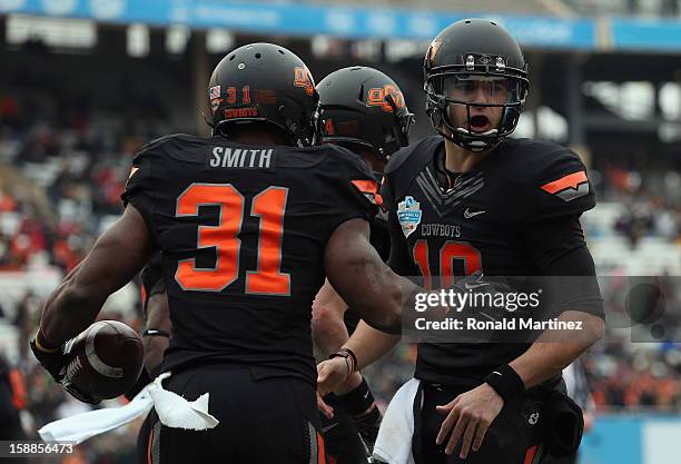 Jeremy Smith of the Oklahoma State Cowboys celebrates a touchdown with Clint Chelf against the Purdue Boilermakers during the Heart of Dallas Bowl at...