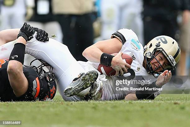 Robert Marve of the Purdue Boilermakers is tackled by Caleb Lavey of the Oklahoma State Cowboys during the Heart of Dallas Bowl at Cotton Bowl on...