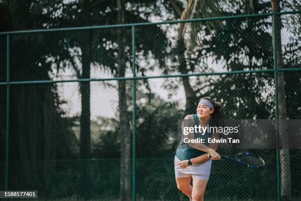 asian chinese female tennis player serving the ball practicing at tennis court - baseline stock pictures, royalty-free photos & images