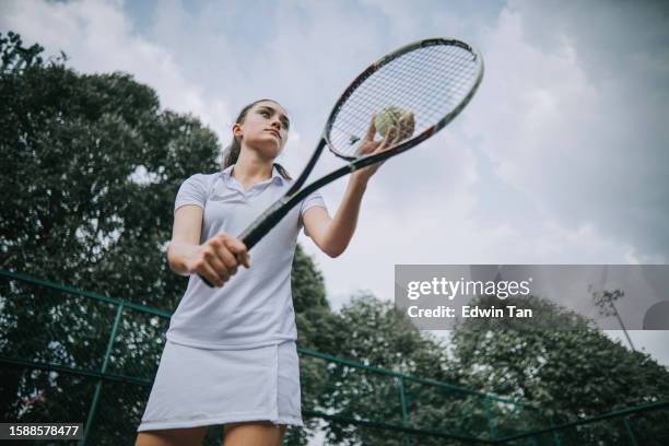 adolescente jugadora de tenis sirviendo en cancha de tenis - atuendo de tenis fotografías e imágenes de stock
