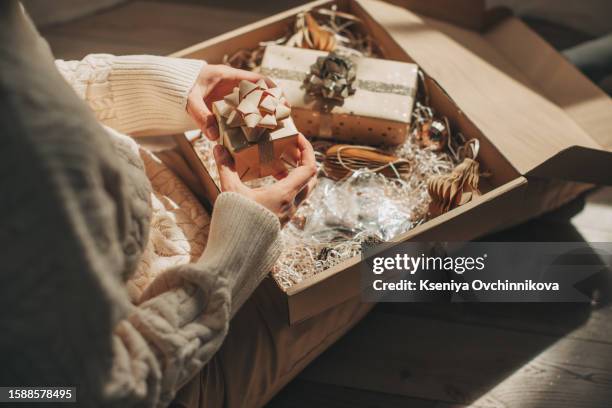 happy woman holding greeting card near parcel with christmas gift at table indoors, closeup - 0 1 monat stock-fotos und bilder
