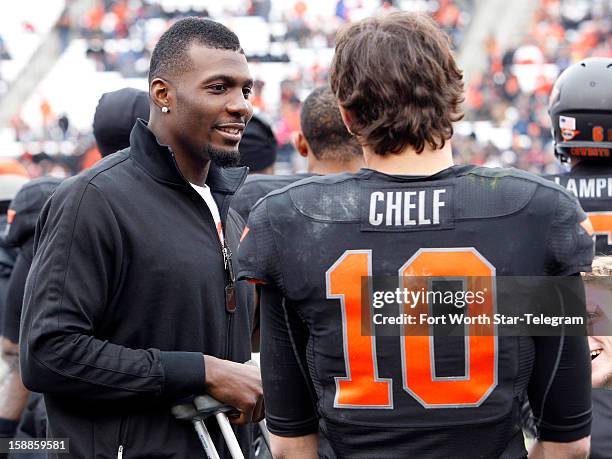 Dallas Cowboys wide receiver Dez Bryant talks with Oklahoma State Cowboys quarterback Clint Chelf during the Heart of Dallas Bowl game against Purdue...