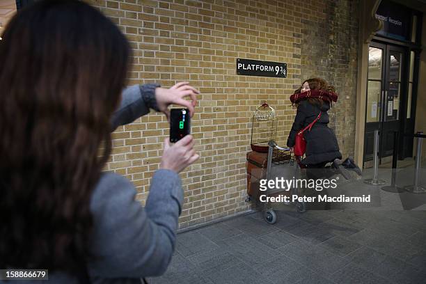 Tourist re-enacts a scene from Harry Potter at Kings Cross station on January 2, 2013 in London, England. Rail fares have today risen by an average...