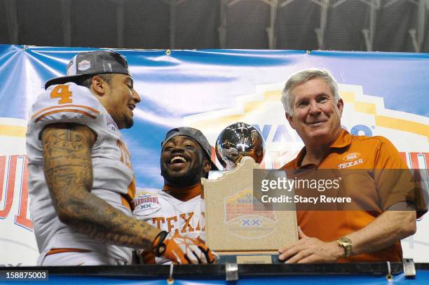 Mack Brown, head coach of the University of Texas Longhorns, and Kenny Vaccaro hold the champions trophy following the Valero Alamo Bowl against the...