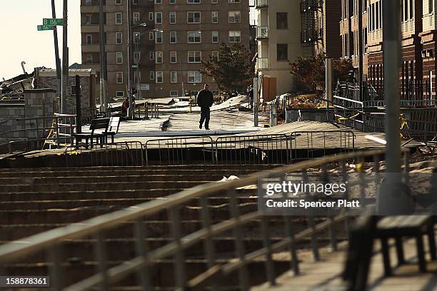 Man walks on the remains of part of the boardwalk along the beach in the Rockaways on January 2, 2013 in the Queens borough of New York City....
