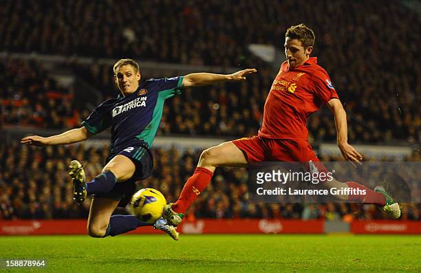 Joe Allen of Liverpool shoots under pressure from Matthew Kilgallon of Sunderland during the Barclays Premier League match between Liverpool and...