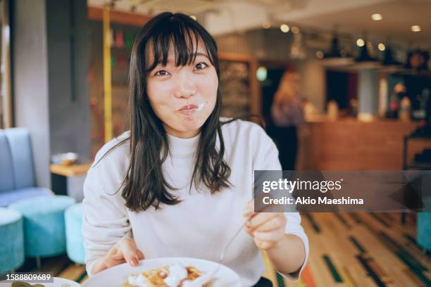 a woman is busy chewing when her friend took this photo - foodie stockfoto's en -beelden