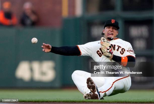 Isan Diaz of the San Francisco Giants from the seat of his pants throws to first base off balance throwing out Jace Peterson of the Arizona...