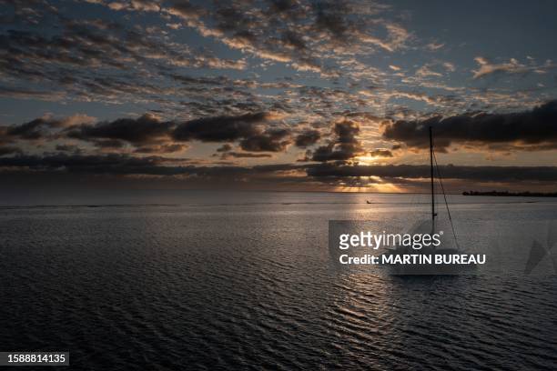 The sun rises over a sailing boat anchored at Tautira bay on August 10 on the island of Tahiti, French Polynesia.