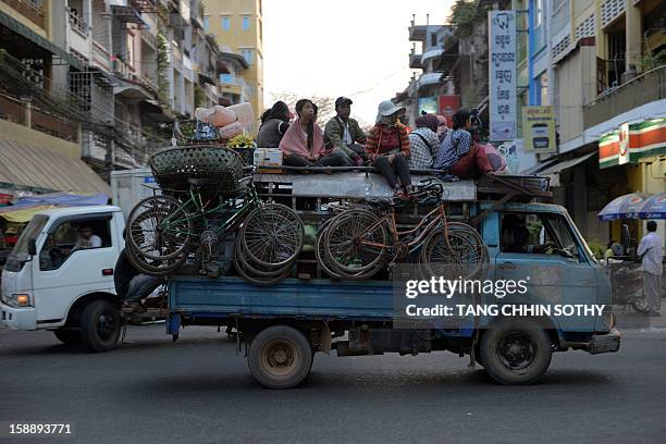 Cambodian people sit on the roof of a truck as it drives along a street in Phnom Penh on January 3, 2013. Written off as a failed state after the...