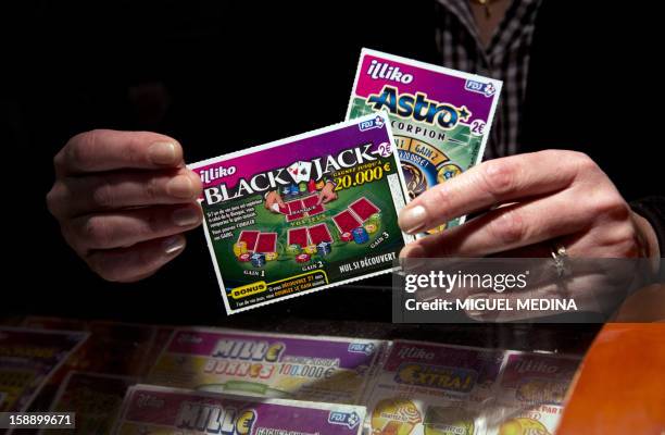 Person holds scratchcard games, January 3, 2013 in Paris. The Française des Jeux , the operator of France's national lottery games, announced on...