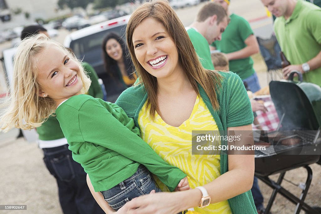 Cute mom and daughter at college football stadium tailgate cookout