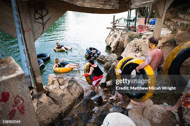 people enter the river in an inner tube - vang vieng stockfoto's en -beelden