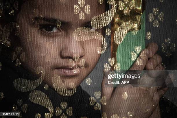 Bahraini Shiite Muslims girl watches the Arbaeen religious festival from a window in the village of Sanabis, west of Manama, on January 3, 2013....
