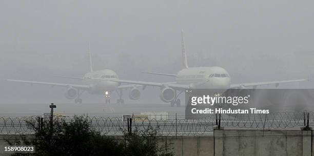 Passengers planes waits at the Runway to take off in dense fog on January 3, 2013 in New Delhi, India. A cold wave is sweeping across north India...
