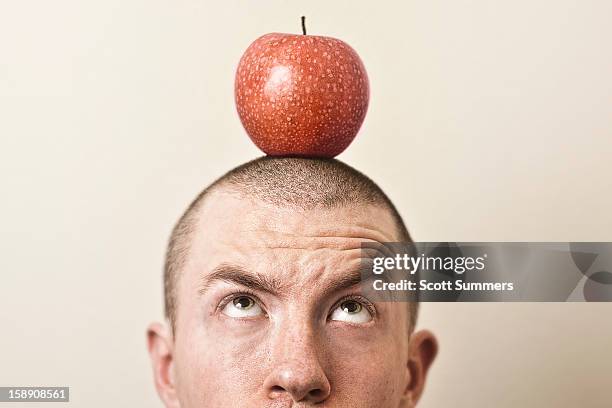 man with a red apple sitting atop his head. - regarder une pomme photos et images de collection