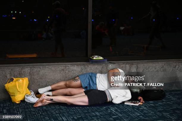 Passengers try to sleep on the floor of the airport terminal while waiting for delayed and canceled flights off the island as thousands of passengers...