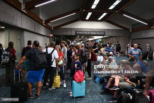 Passengers try to rest and sleep after canceled and delayed flights while others wait to board flights off the island as thousands of passengers were...