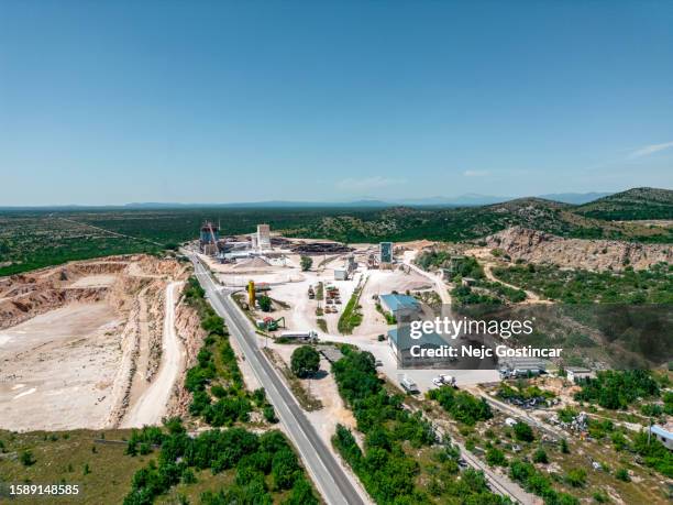 aerial view of a quarry with industrial buildings and heavy machinery - kalksteen stockfoto's en -beelden