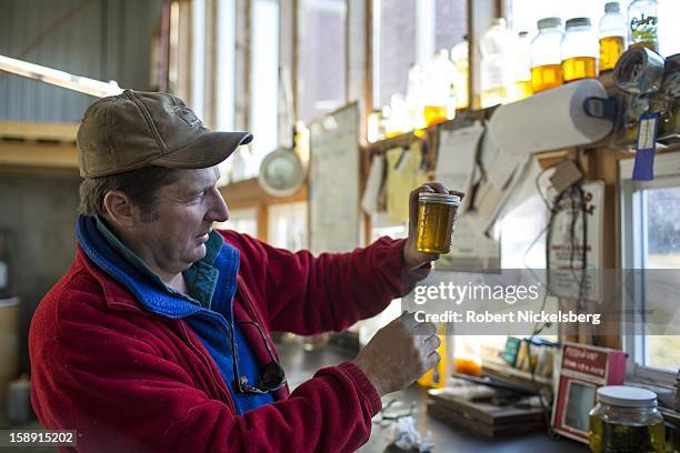 John Williamson inspects a container of freshly crushed flaxseed oil December 14, 2012 on his 200-acre organic farm in North Bennington, Vermont....