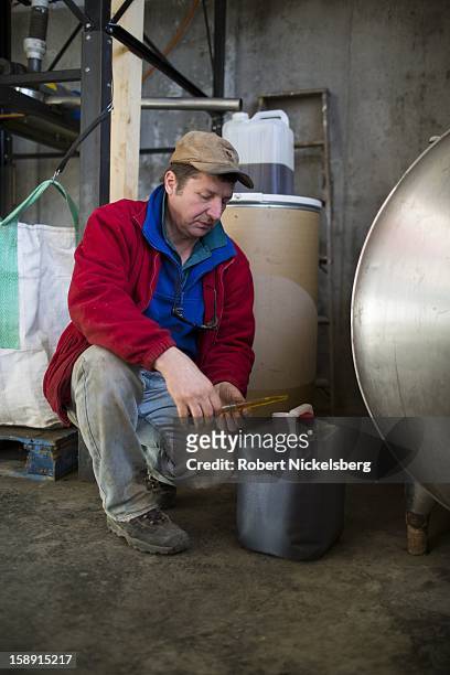 John Williamson inspects a container of freshly crushed flaxseed oil December 14, 2012 on his 200-acre organic farm in North Bennington, Vermont....
