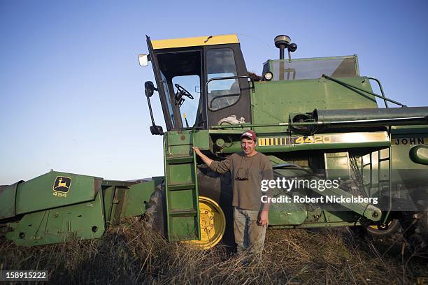 John Williamson stands outside of his combine as he harvests a field of sunflowers on his 200-acre State Line Farm October 17, 2012 in North...