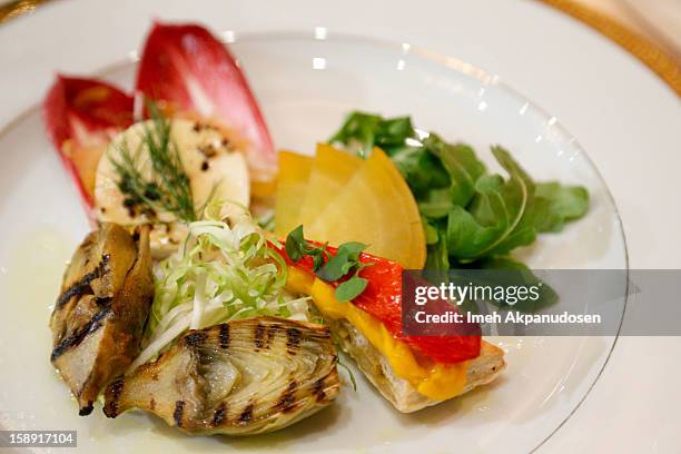 View of the grilled artichoke with fennel tomato lemon mousse and California pepper honey goat cheese on endive pear salad appetizer prepared by...