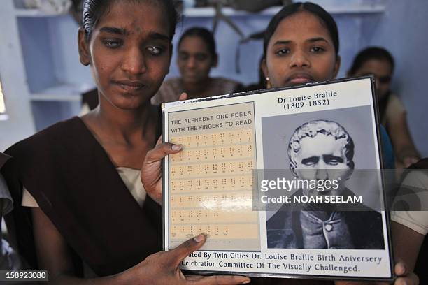 Visually impaired Indian students pose with a portrait of Louis Braille and the Braille alphabets of his invention at the Sai Junior College For The...