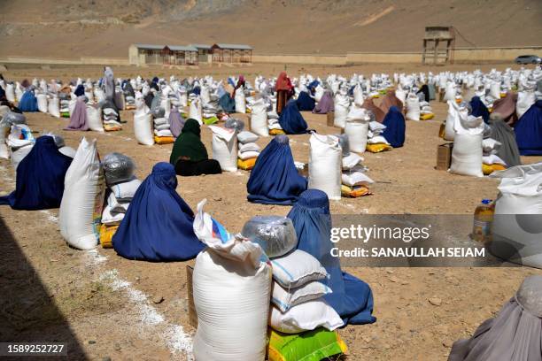 Afghan burqa-clad women receive food from foreign aid in Kandahar on August 10, 2023.