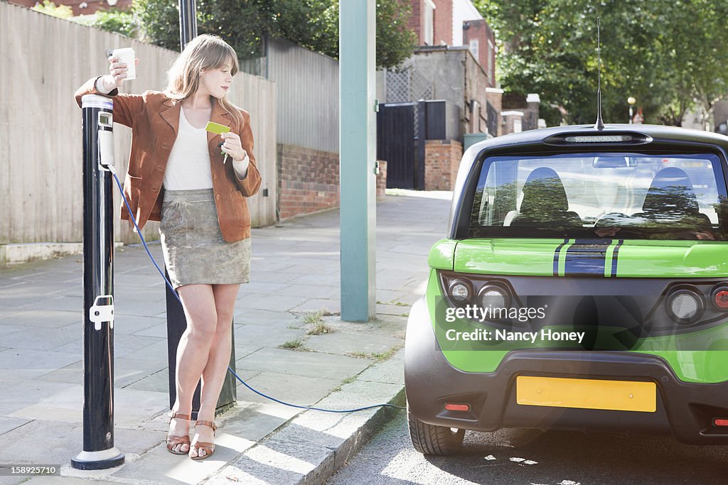 Woman charging electric car on street