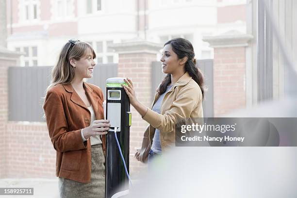 women charging electric car on street - nancy green fotografías e imágenes de stock