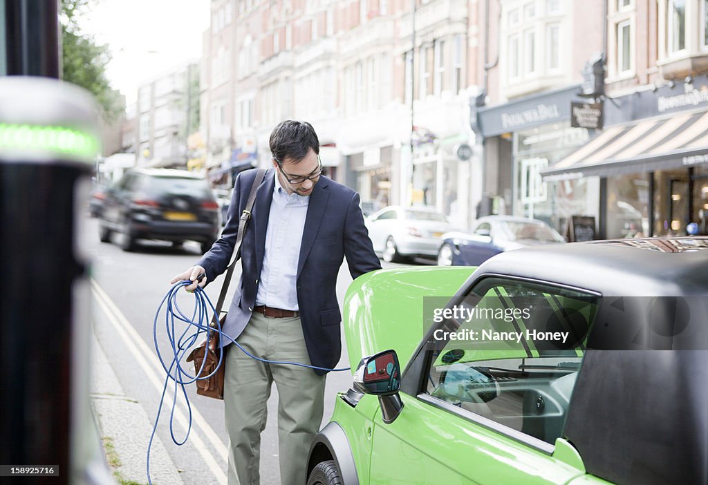 Man charging electric car on street