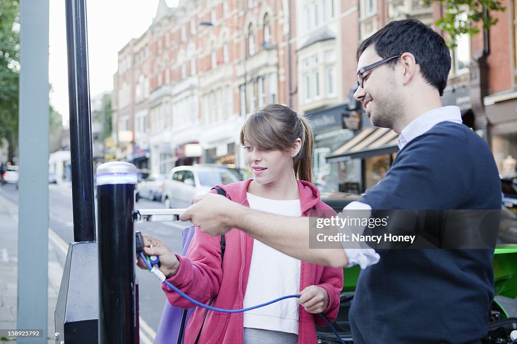 Couple charging electric car on street