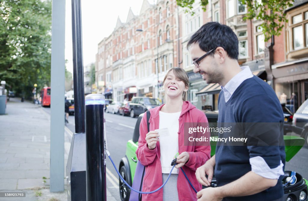 Couple charging electric car on street
