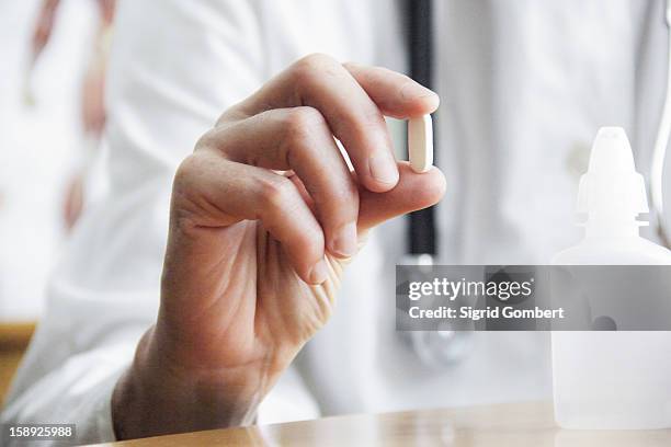 doctor holding pill in office - tablette stock-fotos und bilder