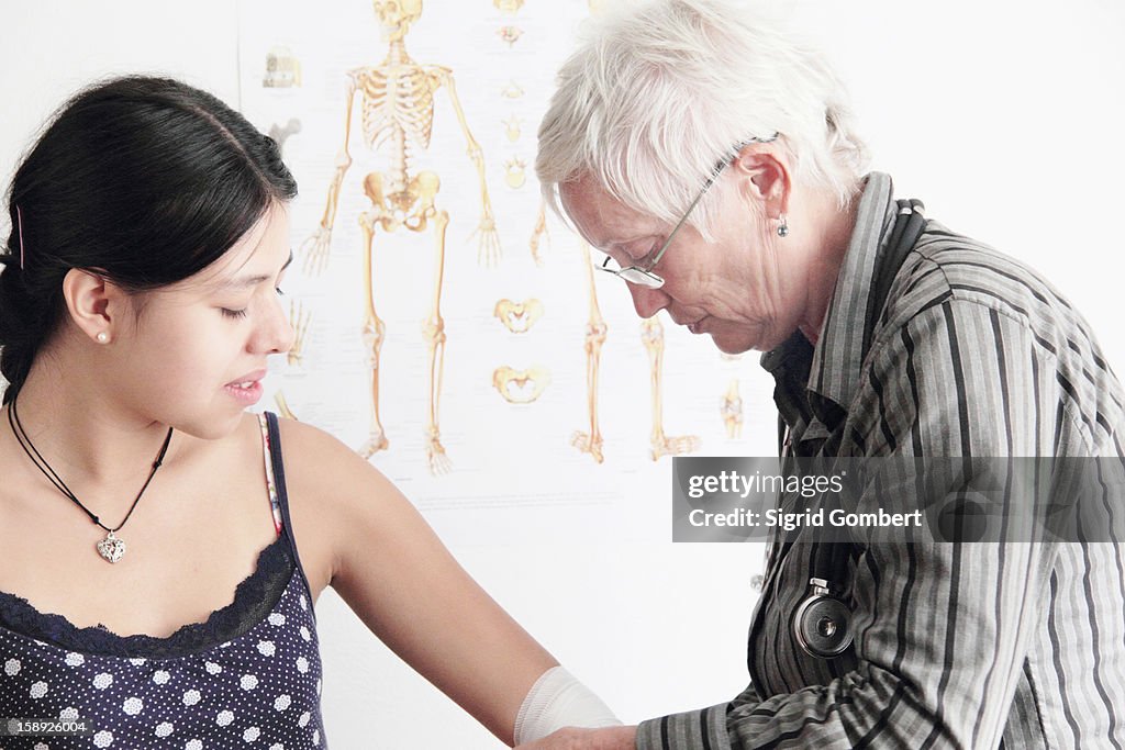 Doctor wrapping teenage girls elbow