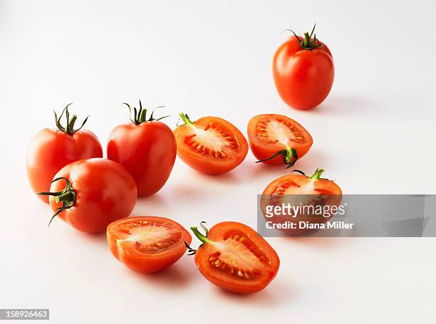 halved plum tomatoes on kitchen counter - tomato stockfoto's en -beelden
