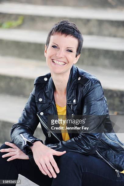 smiling woman sitting on city steps - einzelne frau über 30 stock-fotos und bilder
