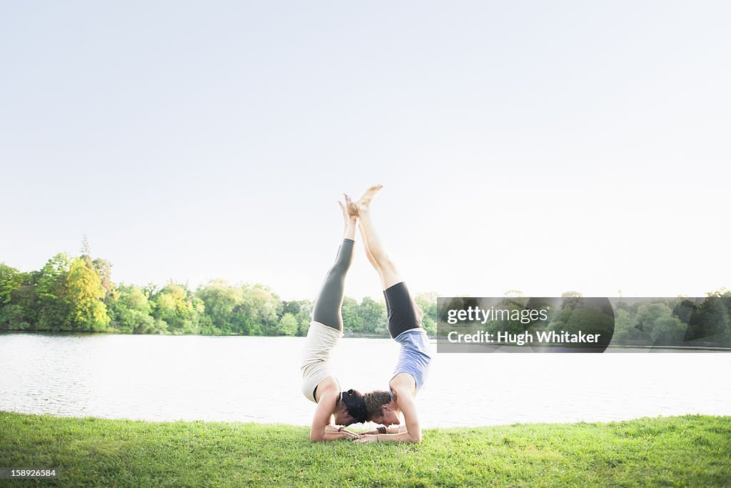 Couple practicing yoga by water