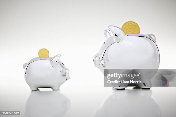 gold coins dropping into piggy banks - gold meets golden stock pictures, royalty-free photos & images